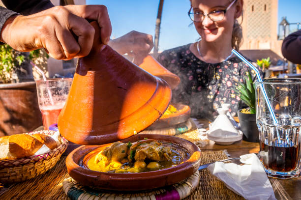 traditional Moroccan tajine with chicken, lemon and olives hand opening a traditional Moroccan tajine with chicken, lemon and olives in the restaurant in Marrakesh moroccan culture stock pictures, royalty-free photos & images