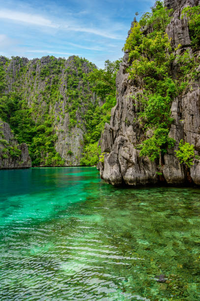 błękitna, kryształowa woda w rajskiej zatoce z łodziami na drewnianym molo nad jeziorem kayangan na wyspie coron, tropikalna destynacja podróży - palawan, filipiny. - kayangan lake zdjęcia i obrazy z banku zdjęć