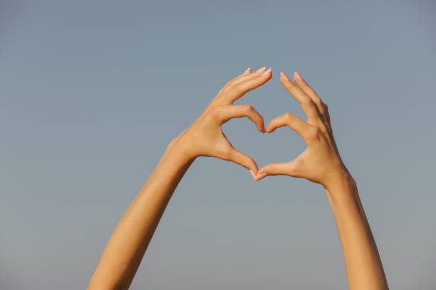istock Human hands making shape of heart in front of sky 1294326662