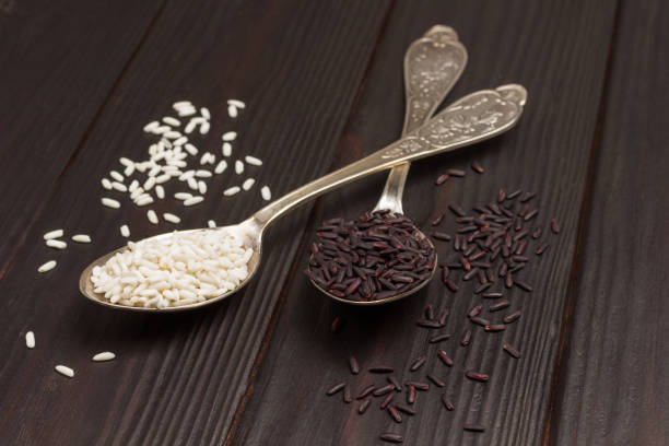 czarny ryż w metalowej łyżce i biały ryż w metalowej łyżce. - carbohydrate rice cereal plant uncultivated zdjęcia i obrazy z banku zdjęć