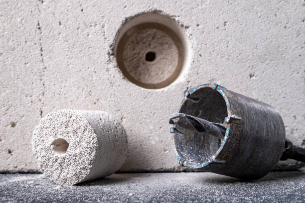 Drilling large diameter holes in brick. Holes for mounting electrical boxes. Dark background.