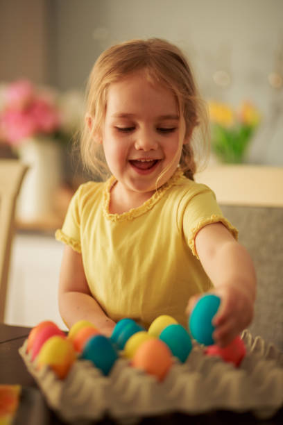 istock Cute girl having fun arranging Easter eggs into egg carton 1294329461