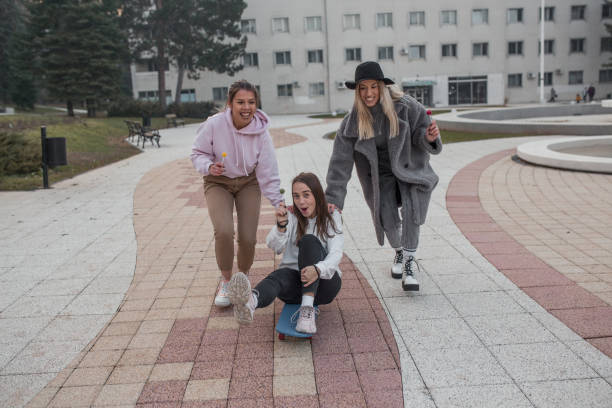 istock Two women pushing their friend on skateboard 1294330320