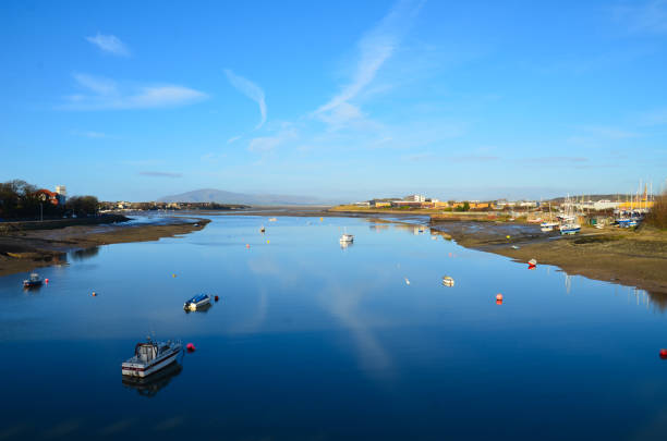 Boats sit moored In shallow water in Barrow-in-Furness.