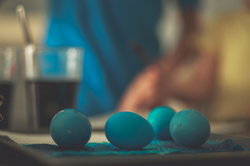 Close up shot of several finished Easter eggs dyed blue drying on a piece of paper towel on the table.