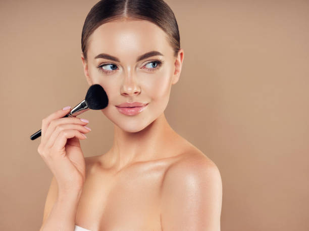 istock Beautiful young woman applying foundation powder 1294330645