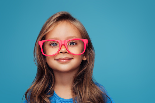 Funny little girl wearing glasses on a colored background