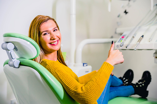 Young happy woman after successful dental treatment in dentist office