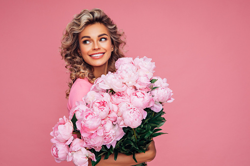 Lovely woman with pink peonies bunch