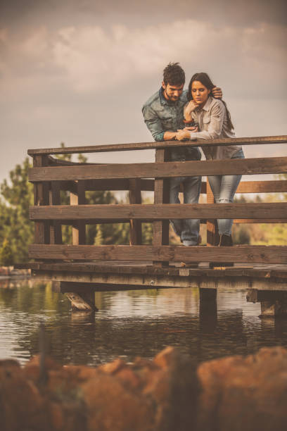 istock Couple standing behind the railing and looking at the lake 1294336545