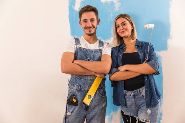 istock Confident couple holding a level and a paint roller smiling at camera 1294337386
