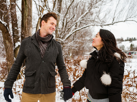 Mixed couple tracking with snowshoes, outdoor activity in winter.