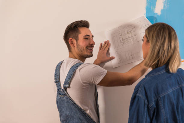 istock Couple deciding on home plans for home renovation while reviewing blueprints 1294337490