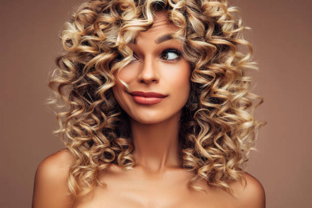 Studio portrait of attractive young woman with voluminous curly hairstyle Studio portrait of attractive young woman with voluminous curly hairstyle curly stock pictures, royalty-free photos & images