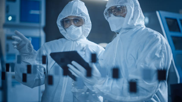 istock Factory Cleanroom: Engineer and Scientist Wearing Coveralls, Standing in Workshop Talk and Use Tablet Computer, Professionals Develop Technology for Modern CNC Machinery and Electronic Equipment 1294339634
