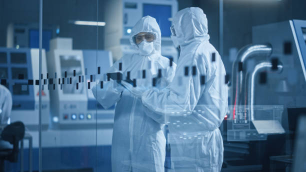 istock Factory Cleanroom: Engineer and Scientist Wearing Coveralls, Standing in Workshop Talk and Use Tablet Computer, Professionals Develop Technology for Modern CNC Machinery and Electronic Equipment 1294339649