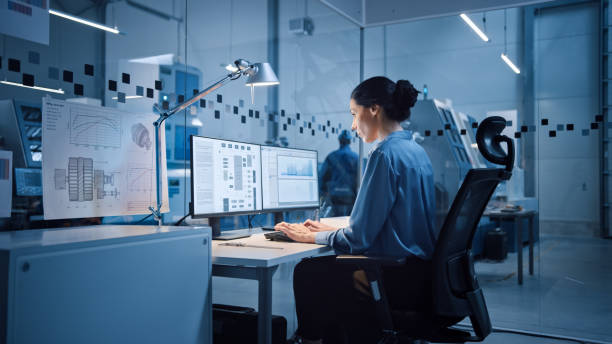 istock Factory Office: Portrait of Beautiful and Confident Female Industrial Engineer Working on Computer, on Screen Industrial Electronics Design Software. High Tech Facility with CNC Machinery 1294339715