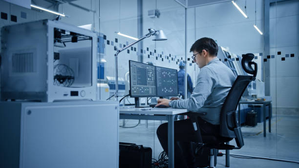 istock Factory Office: Portrait of Beautiful and Confident Male Industrial Engineer Working on Computer, on Screen Industrial Electronics Design Software. High Tech Facility with CNC Machinery 1294339718