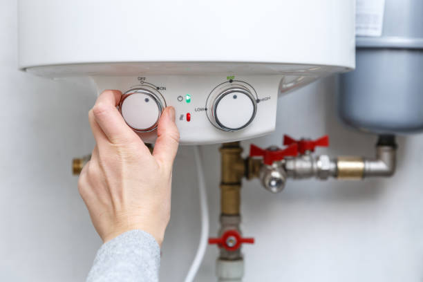 istock Female hand turning on electric water heater (boiler). 1294344009