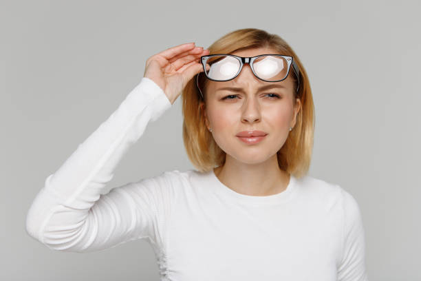 Woman has problems with poor eyesight, squinting while trying to see something Woman has problems with poor eyesight, squinting while trying to see something, takingoff glasses, isolated on gray background. Myopia, hyperopia, vision concept. squint eyes stock pictures, royalty-free photos & images