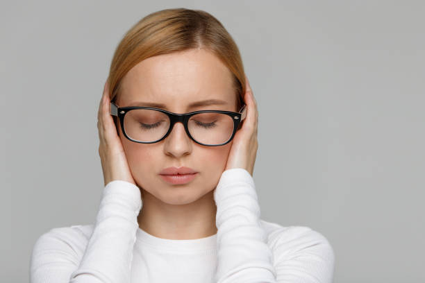 woman shuts ears, close eyes, trying keep calm and take control over emotions - tinitus imagens e fotografias de stock