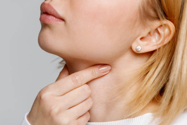 女性は喉の痛みの指に触れる。甲状腺、痛みを伴う嚥下、扁桃炎 - nasopharynx ストックフォトと画像