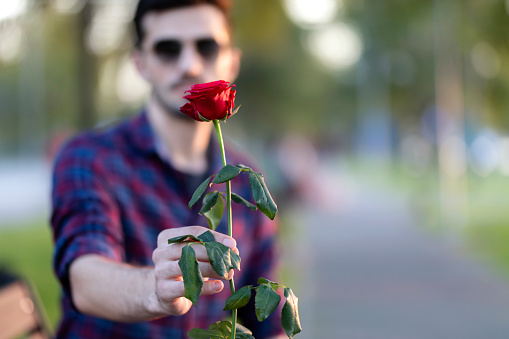 Men is holding red rose