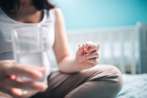 Pregnant woman taking pill at home stock photo