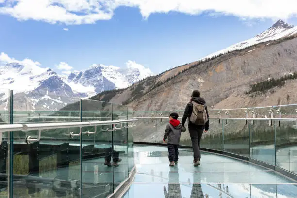 Mother and Son walking on the Columbia Icefield  Skywalk During Summer in Jasper National Park. The footpath is almost empty which is very rare but with the Covid-19 pandemic, less people are traveling. It is a beautiful sunny day. The view on the glacier is majestic.