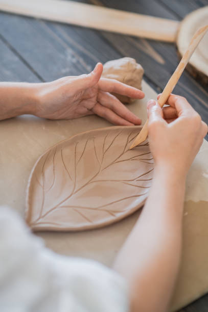 istock Female potters hand making clay pottery at the table with a different wooden tools close up 1294354917