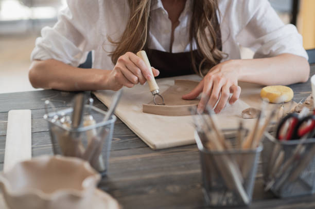 istock Female potters hand making clay pottery at the table with a different wooden tools close up 1294354924