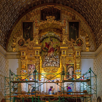 Mexican people doing restoration on a baroque style gold leaf altar piece in the Santo Domingo church and convent, Oaxaca, Mexico.