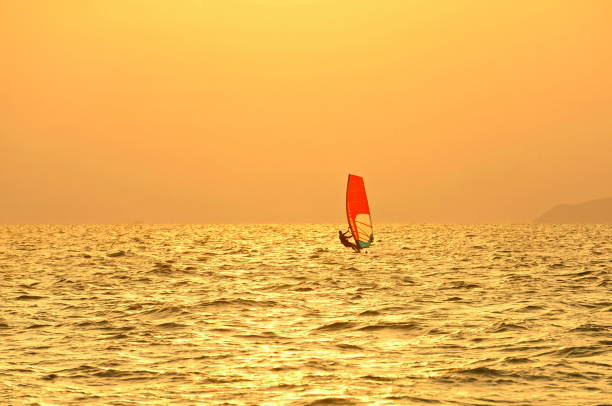 istock Windsurfing at sea. Red sail against a pink sunset. 1294364692