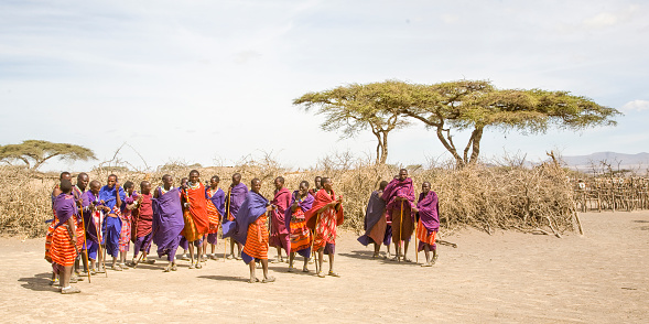 Group of Maasai, men, women and children  in village close to Serengeti Tanzania.