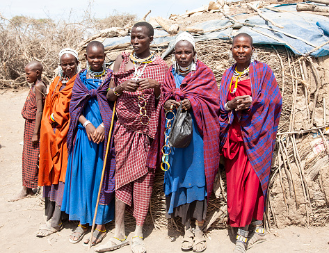 Group of Maasai, men and women standing outside their hut in village close to Serengeti Tanzania.