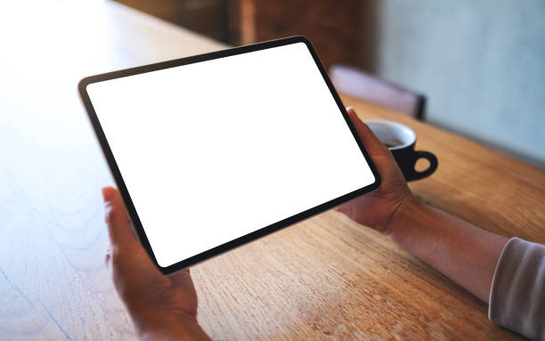 istock a woman holding digital tablet with blank white desktop screen with coffee cup on wooden table 1294371446