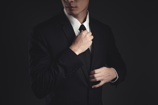 Close up shot of businessman in black suit. Elegant handsome on black background.