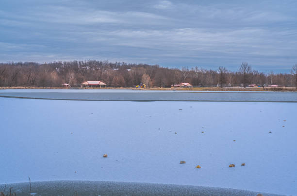 View of frozen Midwestern lake after snowfall; residential park on the other side of the lake