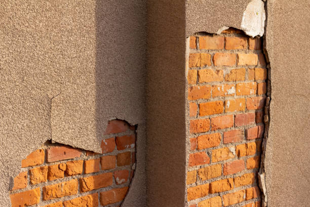 istock Texture background of an old clay brick wall underneath a deteriorating sand color stucco plaster 1294372049