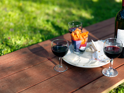 Picnic on the bench with red wine and cheese, shallow dof