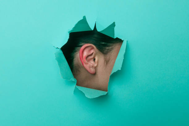 istock Female ear close-up. Copy space. Torn paper, blue background. 1294390643