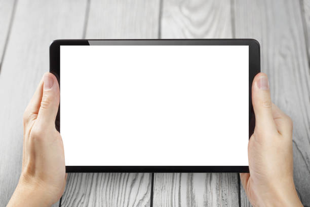 istock Hands with black tablet on light gray wood 1294392192
