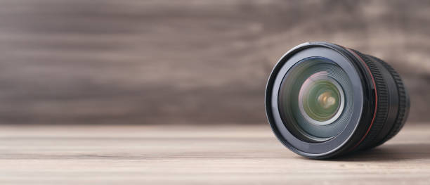istock Camera lens on the wooden table. 1294392245