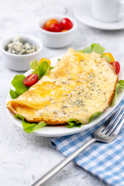 Fried eggs with cheese, cherry tomatoes and fresh lettuce. Omelet with filling for breakfast. Healthy or ketogenic or no carbohydrate food concept. stock photo