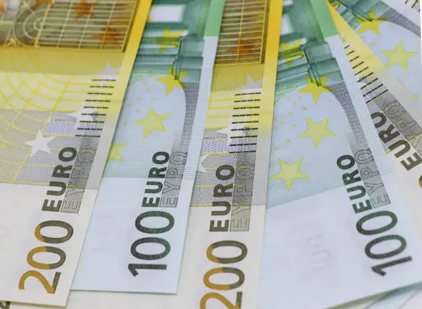 Money background from banknotes in denominations of 100 and 200 euros. Euro money is fanned out on the surface. Top view, close-up