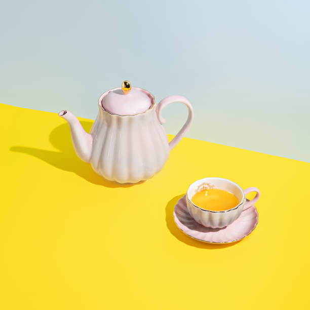 istock Teapot with cup of tea on multi colored pastel blue and yellow background 1294396198
