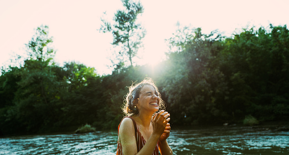 Photo of a young woman bathing in the river and enjoying her time outdoors, on a hot sunny day.