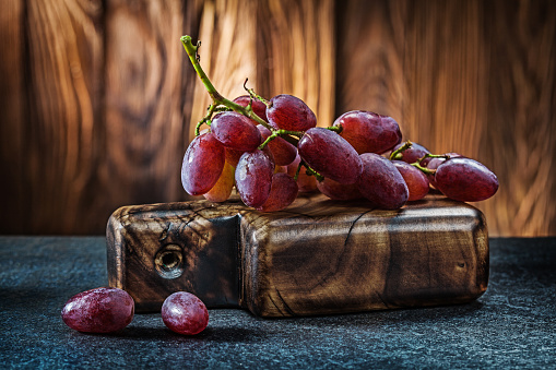 little bunch of rose grape on small vintage carving board and wooden background