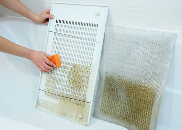Woman cleaning kitchen hood filter in bath tub with sponge Woman cleaning kitchen hood filter in bath tub with sponge kitchen hood stock pictures, royalty-free photos & images