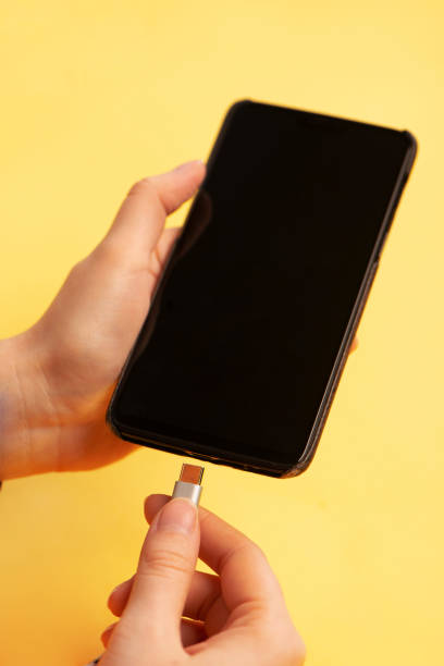 istock Hand connecting type c charging cable to the smartphone on yellow background close up 1294398923